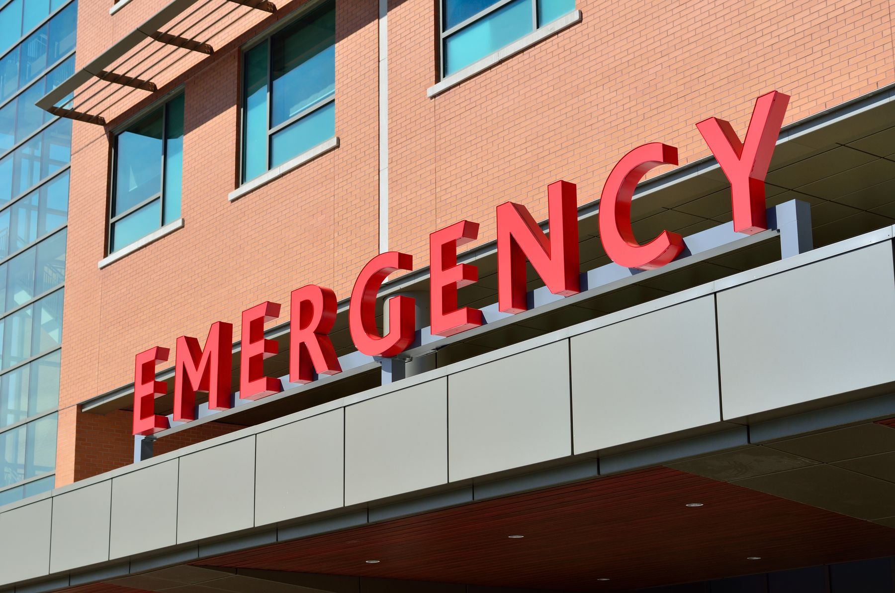 Hospital entrance with clear red emergency signage on a brick and glass exterior