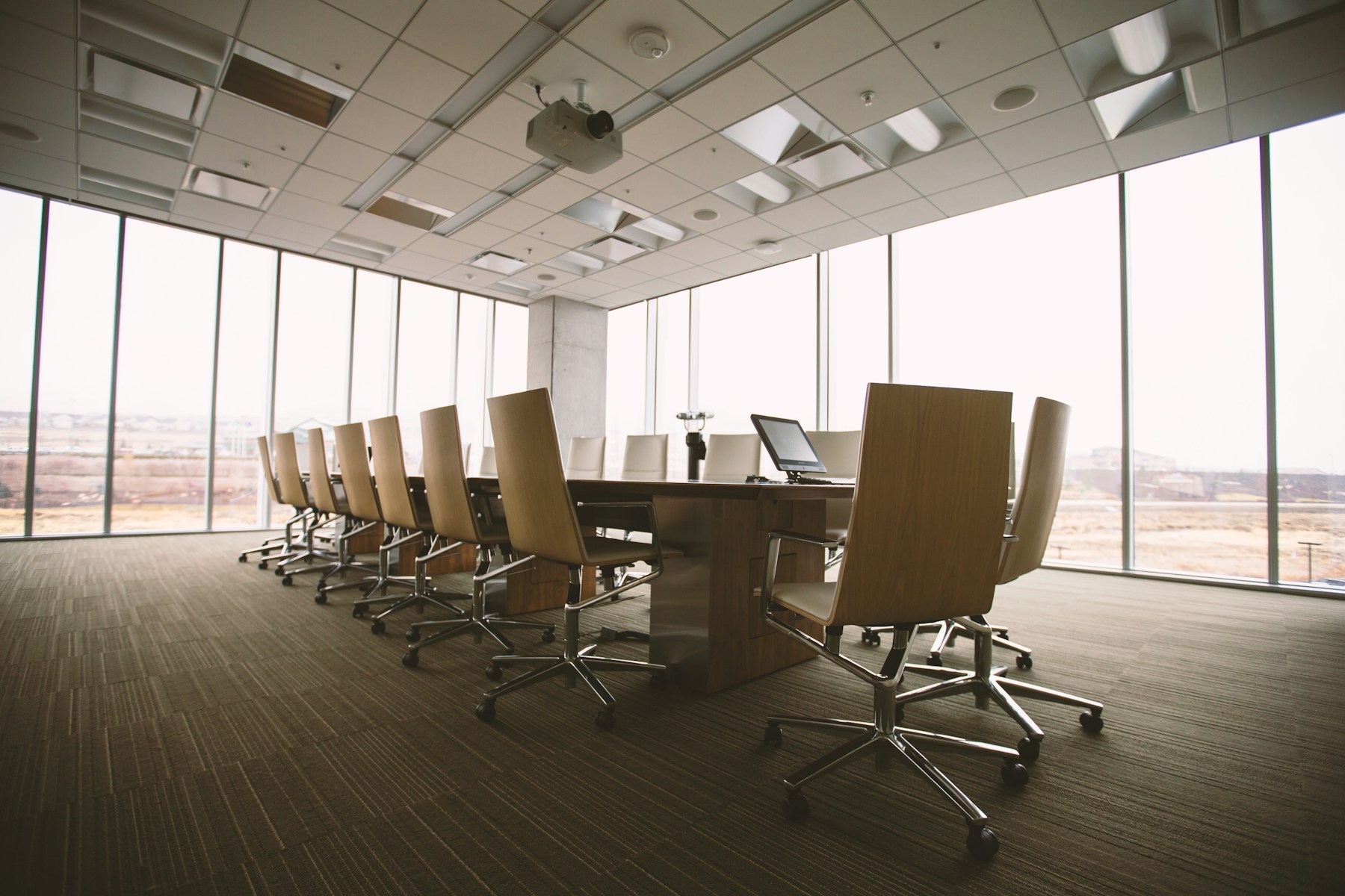 Bright corporate boardroom with a conference table, office chairs and floor-to-ceiling windows